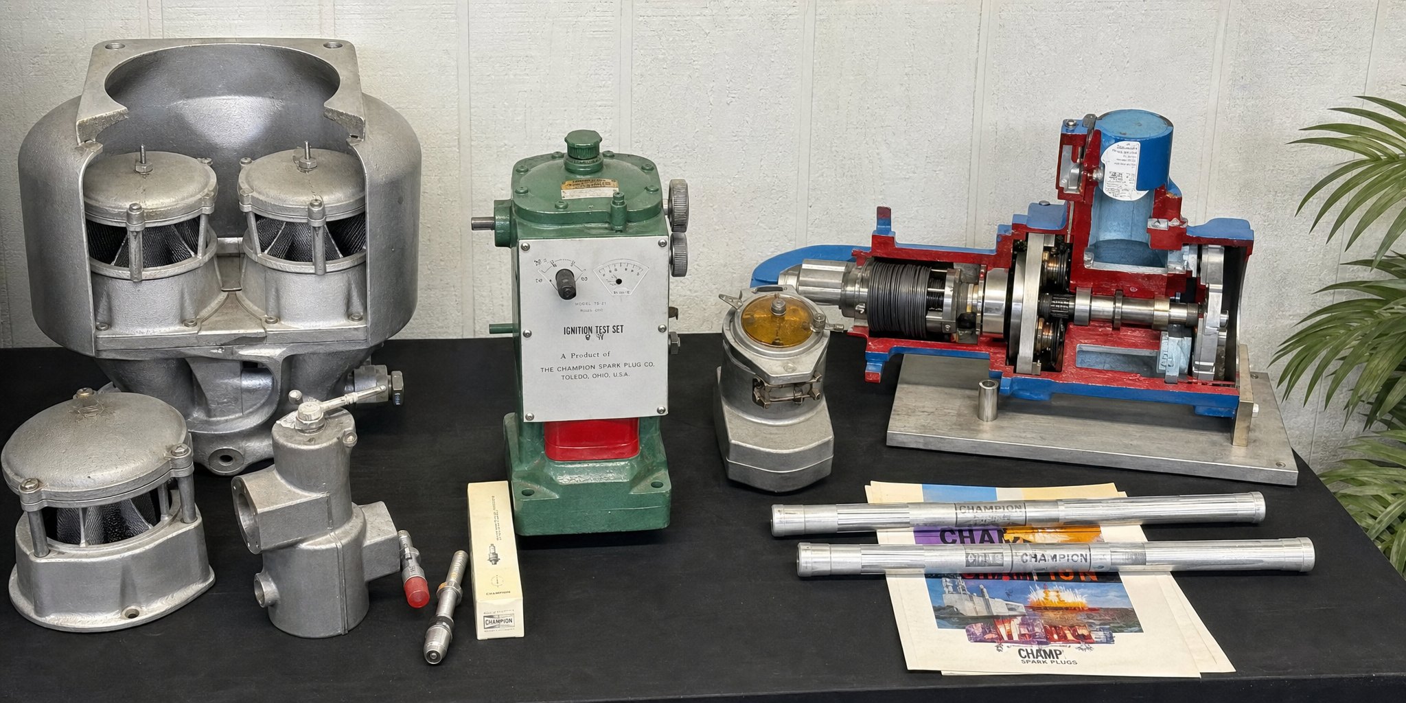 Carburetors, an ignition test stand and a sectioned air starter displayed on a workbench